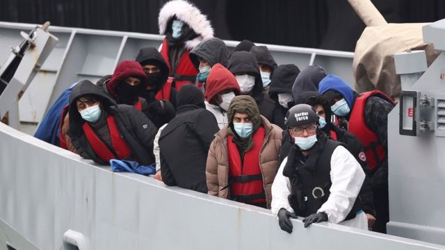 Migrants onboard a Border Force rescue boat wait to disembark at Dover harbour