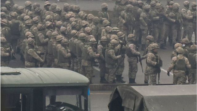 Kazakh law enforcement officers gather in a square during a protest against LPG cost rise